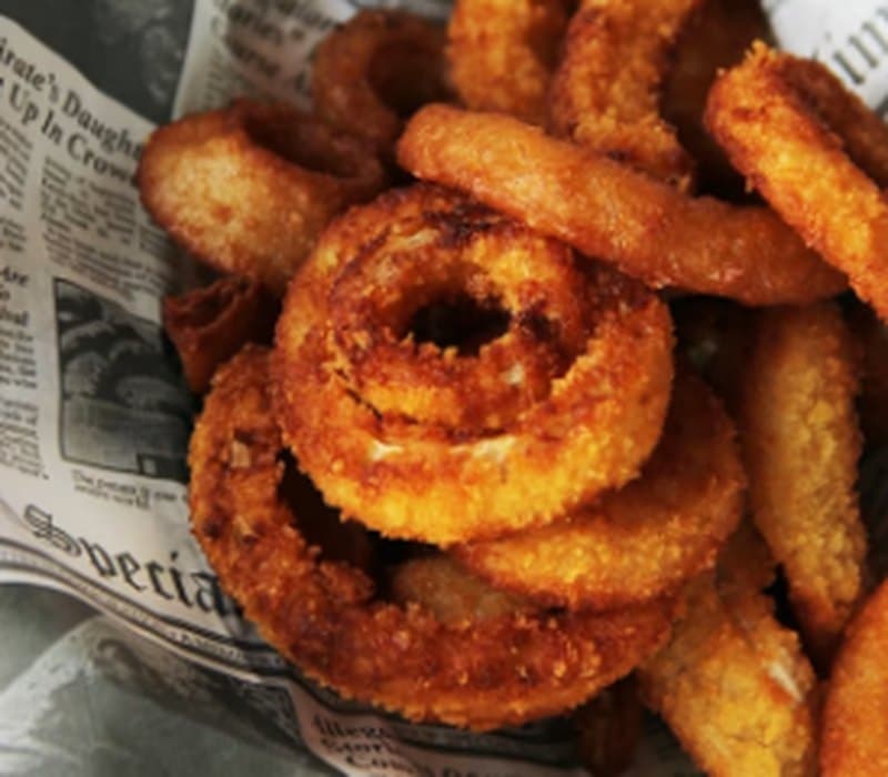 Basket of golden loaded fries and onion rings